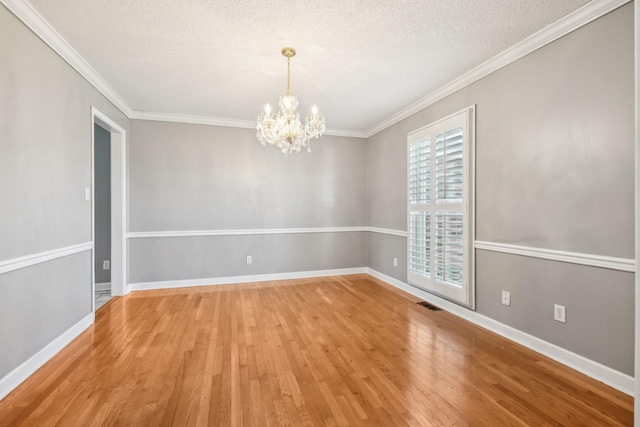 empty room with an inviting chandelier, visible vents, light wood-type flooring, and a textured ceiling