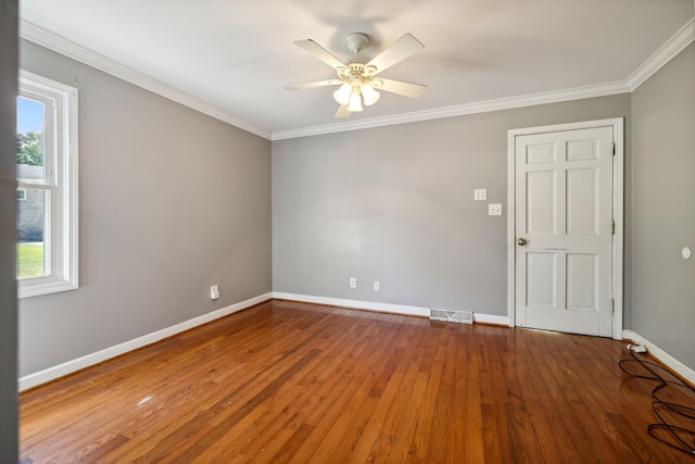 empty room featuring crown molding, wood finished floors, visible vents, and baseboards