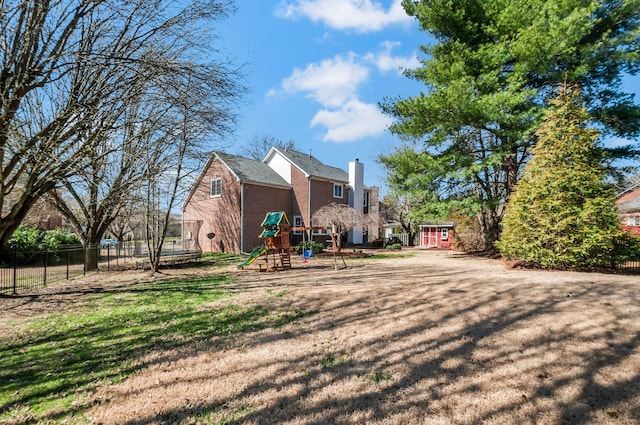 rear view of house featuring a yard, a playground, a trampoline, and fence