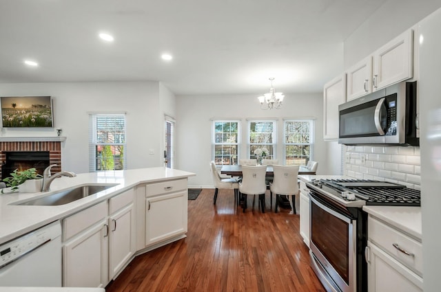 kitchen featuring a sink, decorative backsplash, dark wood-type flooring, stainless steel appliances, and a chandelier