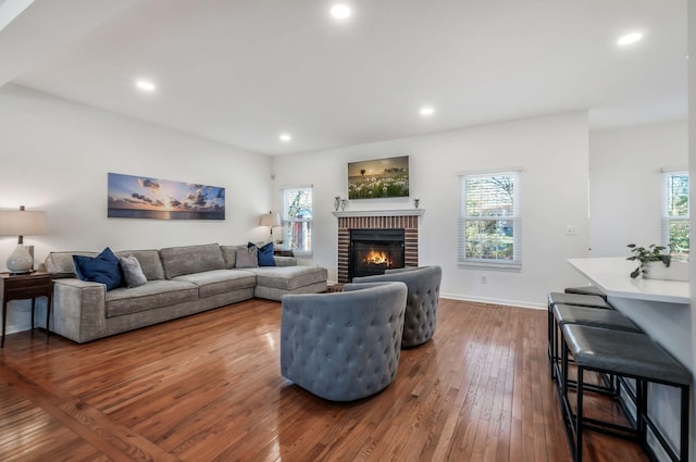 living room featuring plenty of natural light, a fireplace, and dark wood-style flooring