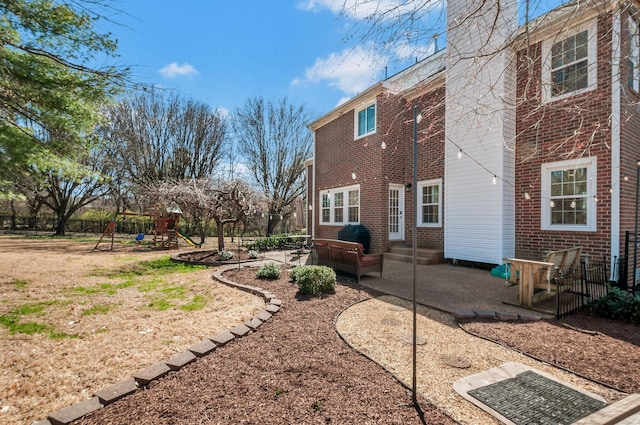 back of house with a patio area, entry steps, a playground, and brick siding