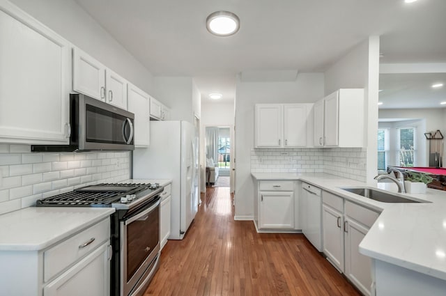 kitchen with a sink, wood finished floors, white cabinetry, and stainless steel appliances