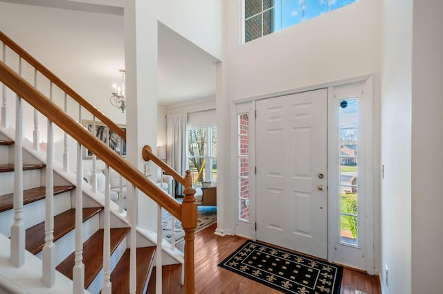 entryway with a notable chandelier, stairs, a high ceiling, and wood finished floors