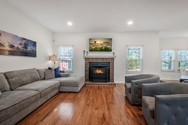 living area with a healthy amount of sunlight, a fireplace, and hardwood / wood-style flooring