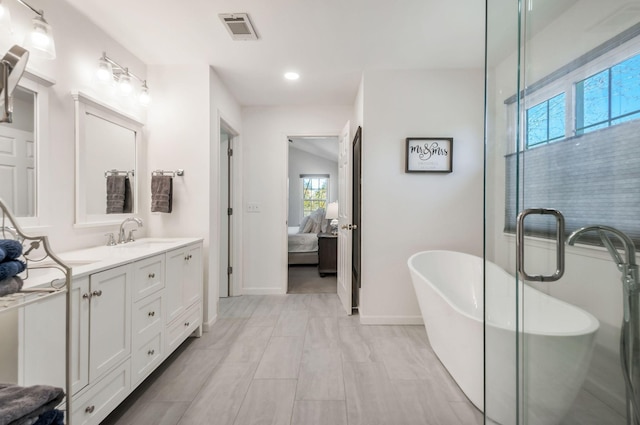 ensuite bathroom with visible vents, baseboards, ensuite bath, a soaking tub, and vanity