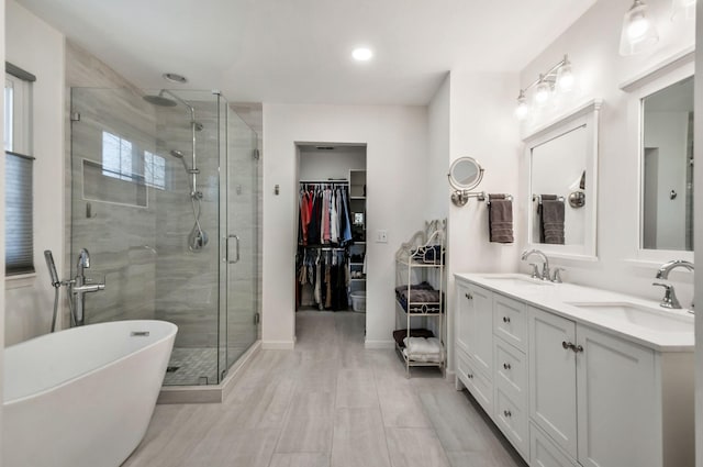 full bath featuring a freestanding bath, double vanity, a stall shower, and a sink