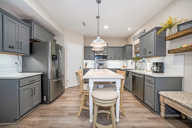 kitchen with open shelves, light wood-type flooring, appliances with stainless steel finishes, and light countertops