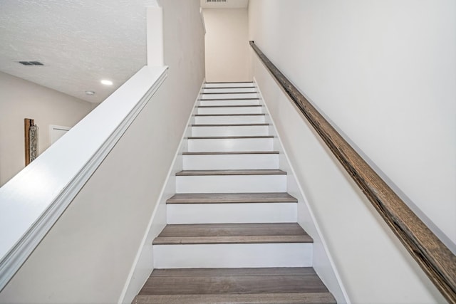 stairs featuring visible vents and a textured ceiling