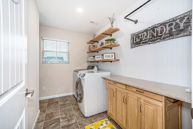 washroom featuring visible vents, stone finish floor, washer and clothes dryer, cabinet space, and baseboards