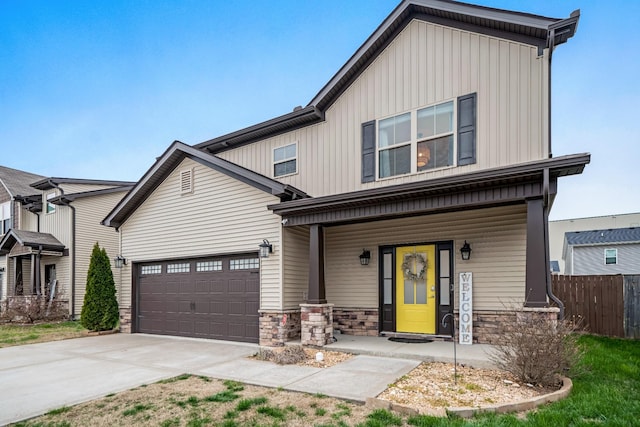 view of front of house featuring fence, covered porch, concrete driveway, stone siding, and board and batten siding