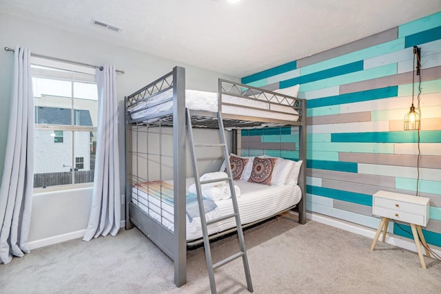 carpeted bedroom featuring visible vents, baseboards, and wooden walls