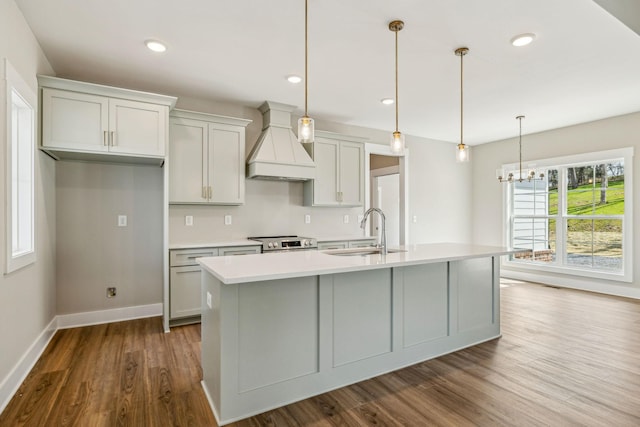 kitchen featuring a sink, light countertops, custom range hood, stainless steel electric range, and a kitchen island with sink