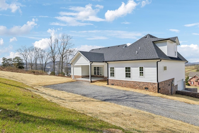 exterior space with driveway and a shingled roof