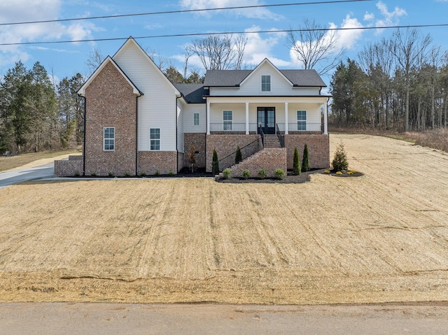 view of front of house with brick siding, a porch, and a front yard