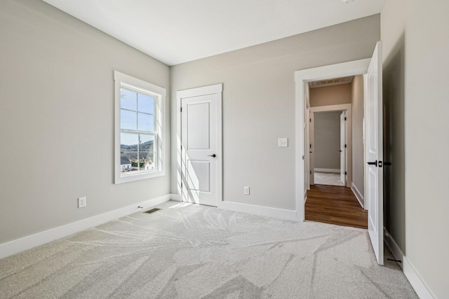 unfurnished bedroom featuring visible vents, baseboards, and carpet floors