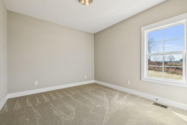 unfurnished room featuring carpet, visible vents, and baseboards