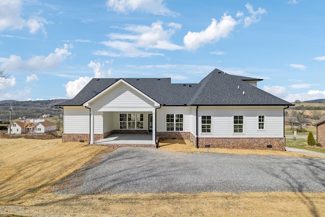 view of front facade featuring a shingled roof, a front lawn, driveway, crawl space, and a mountain view