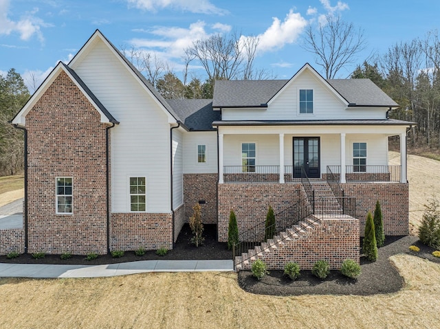 view of front of house featuring stairs, a front lawn, brick siding, and covered porch