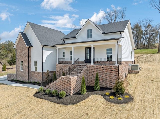 view of front facade featuring a porch, stairway, cooling unit, and brick siding