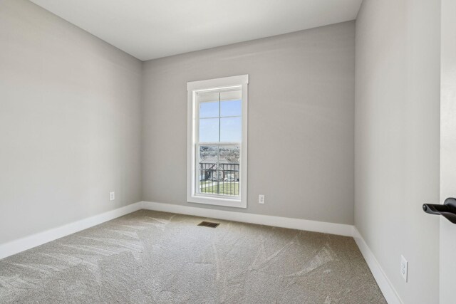 carpeted spare room with visible vents and baseboards