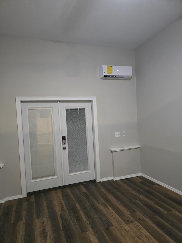 unfurnished room with a wall mounted AC, baseboards, and dark wood-style flooring