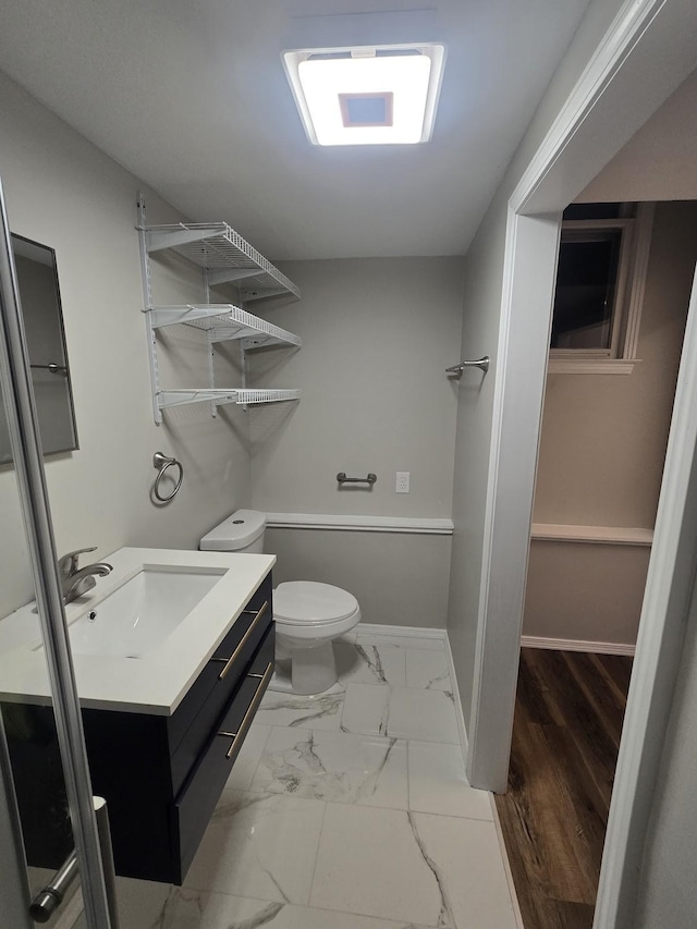 bathroom featuring baseboards, toilet, marble finish floor, and vanity