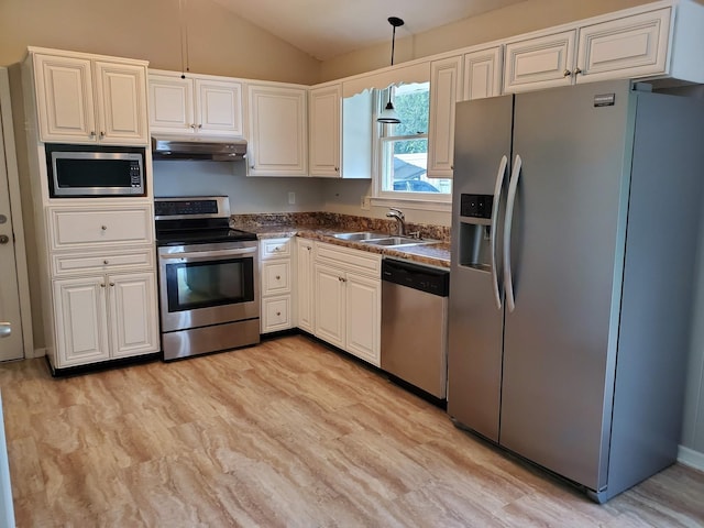 kitchen featuring under cabinet range hood, a sink, dark countertops, appliances with stainless steel finishes, and vaulted ceiling