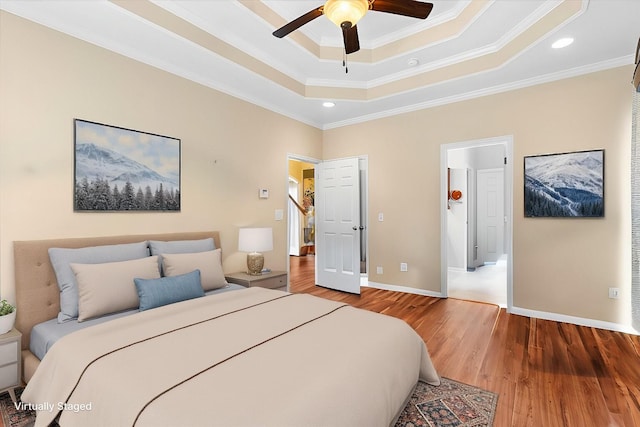 bedroom featuring crown molding, wood finished floors, a raised ceiling, baseboards, and recessed lighting
