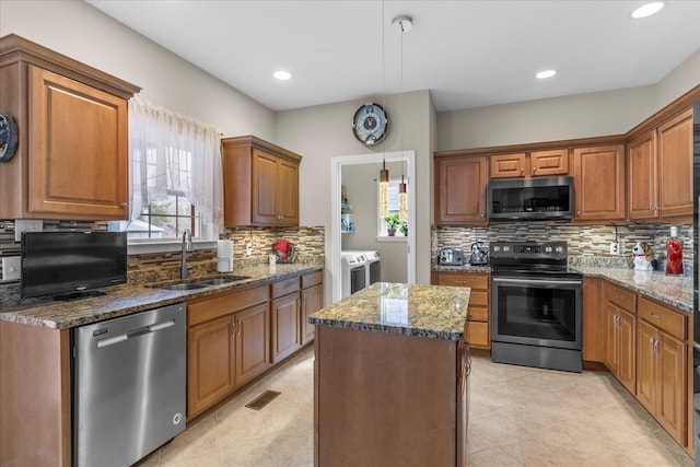 kitchen featuring independent washer and dryer, appliances with stainless steel finishes, a wealth of natural light, and a sink