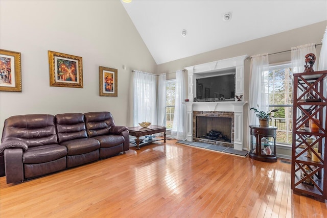 living room with high vaulted ceiling, hardwood / wood-style flooring, and a fireplace