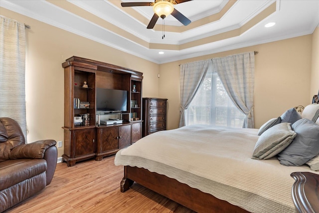 bedroom with crown molding, a ceiling fan, a tray ceiling, and light wood-style floors