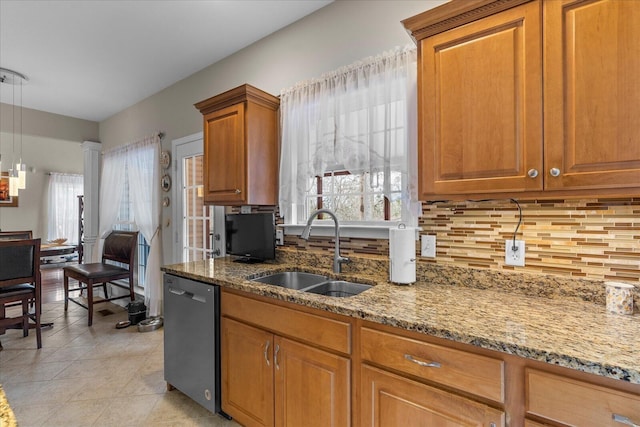 kitchen with brown cabinets, light stone countertops, a sink, backsplash, and stainless steel dishwasher