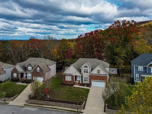view of front facade featuring a garage, a front lawn, brick siding, concrete driveway, and a view of trees