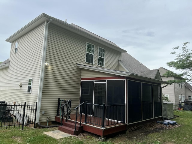 back of property with a sunroom, a shingled roof, and fence