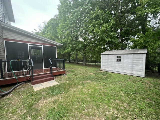 view of yard featuring fence, a deck, a sunroom, a storage shed, and an outbuilding