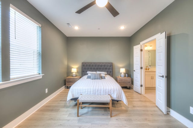 bedroom with ensuite bath, baseboards, visible vents, and light wood finished floors