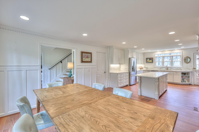 unfurnished dining area with recessed lighting, stairs, light wood-style floors, and a sink