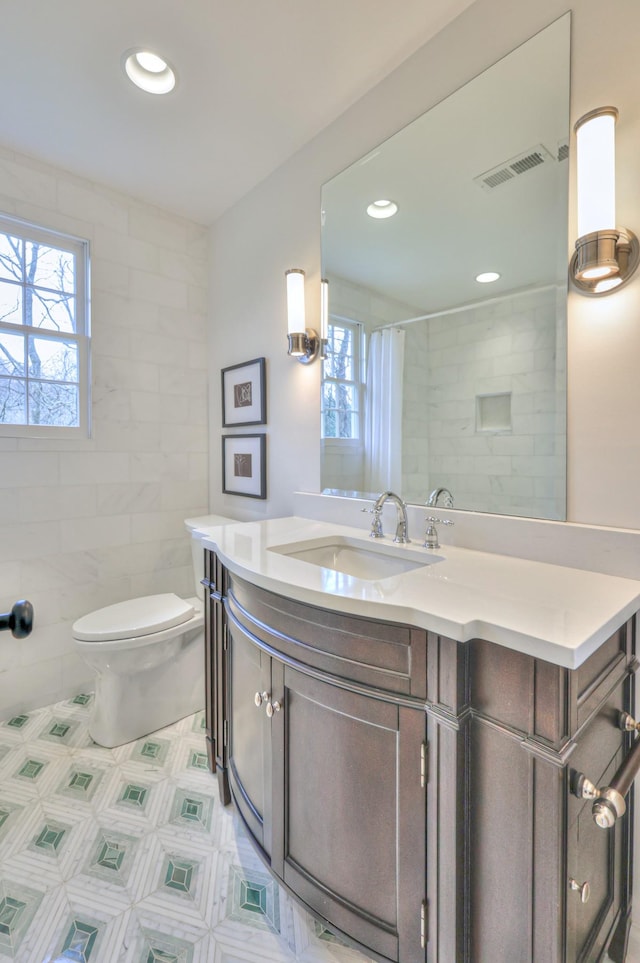 full bathroom featuring vanity, visible vents, recessed lighting, tile walls, and toilet