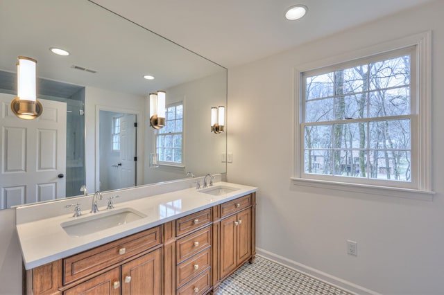 bathroom with double vanity, visible vents, baseboards, and a sink