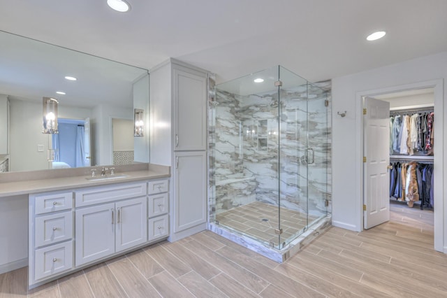 full bath with recessed lighting, a stall shower, vanity, and wood finish floors