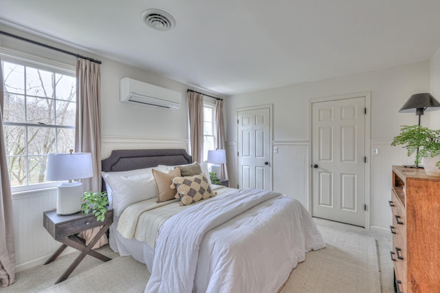 carpeted bedroom with visible vents, a closet, wainscoting, and a wall unit AC