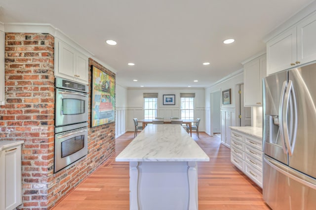 kitchen featuring light wood-style floors, appliances with stainless steel finishes, white cabinets, and a center island