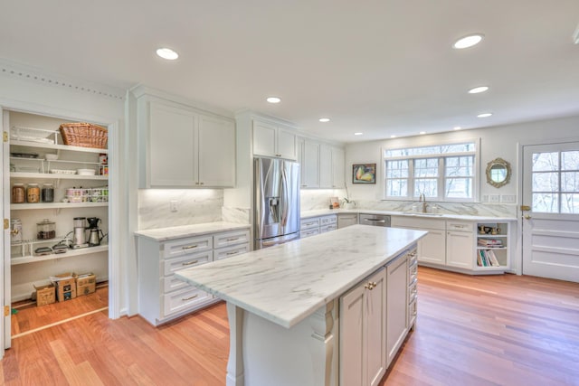 kitchen featuring light wood-type flooring, stainless steel appliances, white cabinets, and a sink