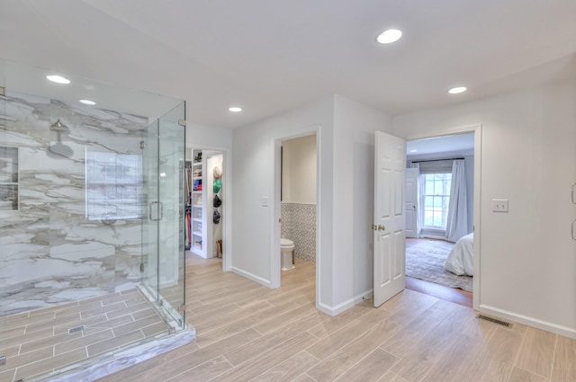 bathroom with wood finish floors, visible vents, baseboards, and a shower stall