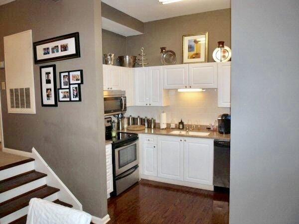 kitchen featuring a sink, light countertops, appliances with stainless steel finishes, white cabinets, and dark wood-style flooring