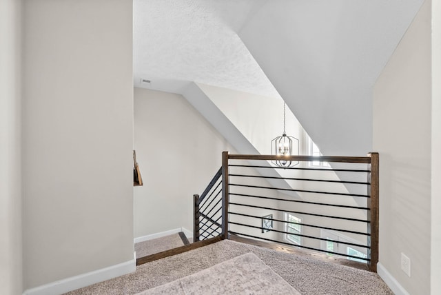 stairway with lofted ceiling, baseboards, carpet, and an inviting chandelier