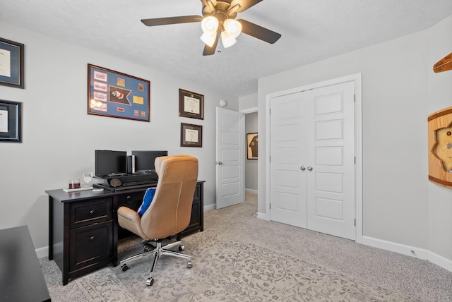 office featuring baseboards, light carpet, a textured ceiling, and ceiling fan