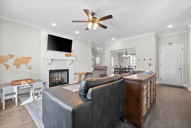 living area featuring recessed lighting, ceiling fan with notable chandelier, a large fireplace, and wood finished floors