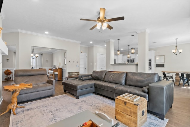 living room featuring crown molding, recessed lighting, ceiling fan with notable chandelier, and light wood finished floors